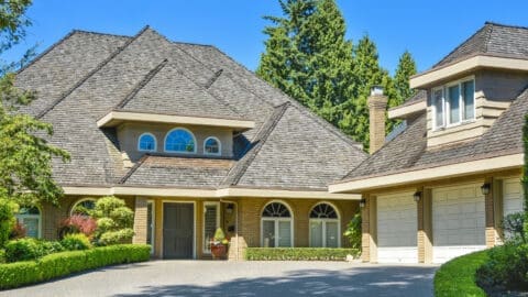 A beautiful, multi-story house is seen with a tan architectural shingle roof.
