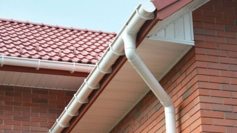 A beautiful soffit and fascia are shown on the side of a residential sloped roof with red tile.