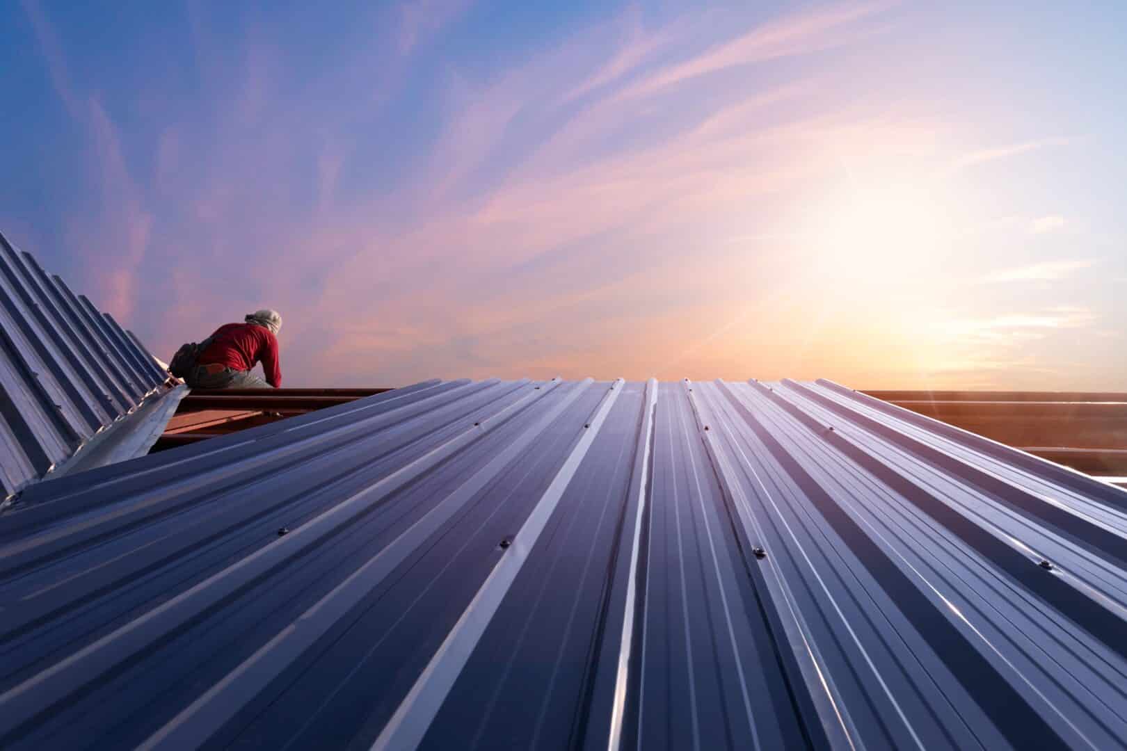 a construction worker on a roof is installing a metal roof